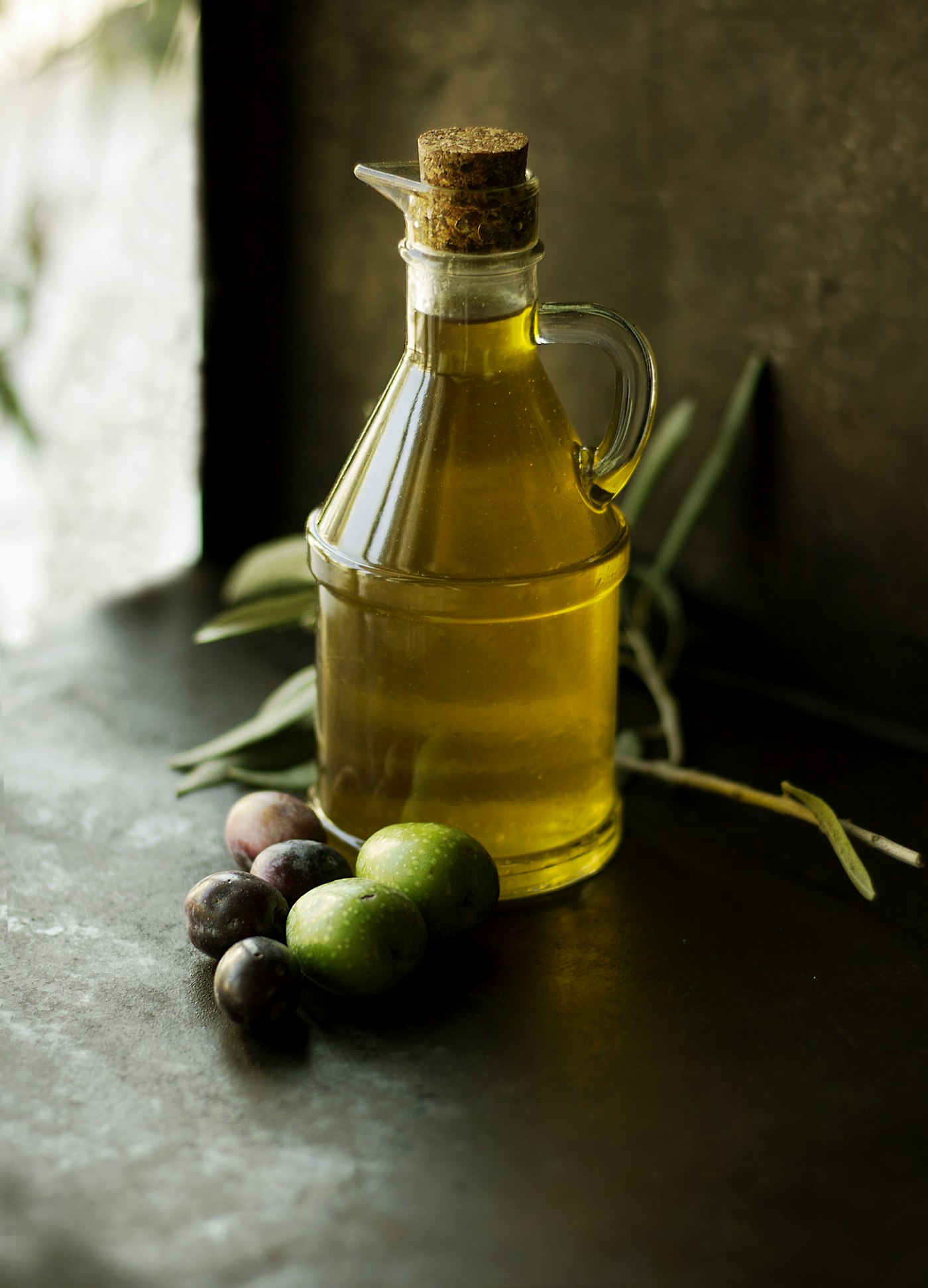 Olive oil poured beside fresh herbs